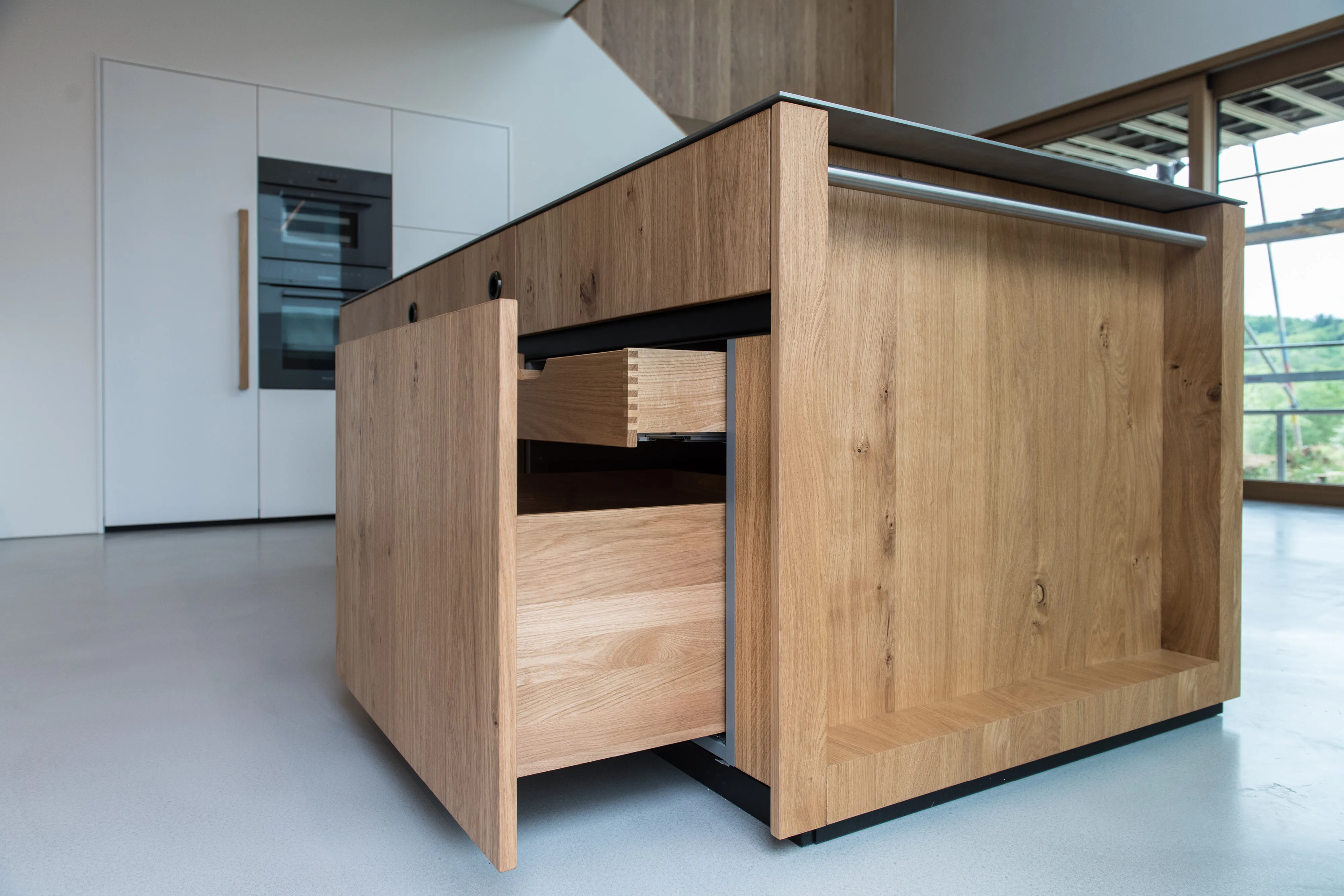 Detailaufnahme einer Echtholz-Kücheninsel mit geöffneten Holzschubladen und Zinkenverbindung