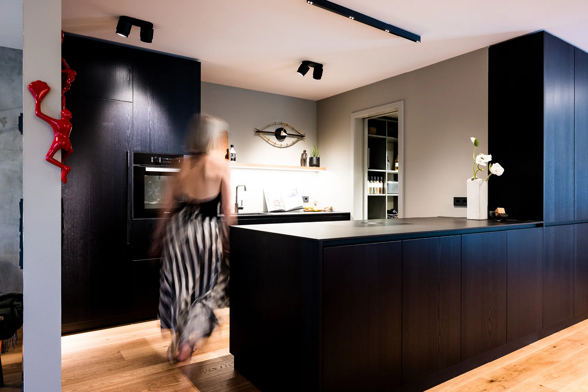 Moderne schwarze Küche mit Kochinsel, integrierten Einbaugeräten und stimmungsvoller LED-Beleuchtung.