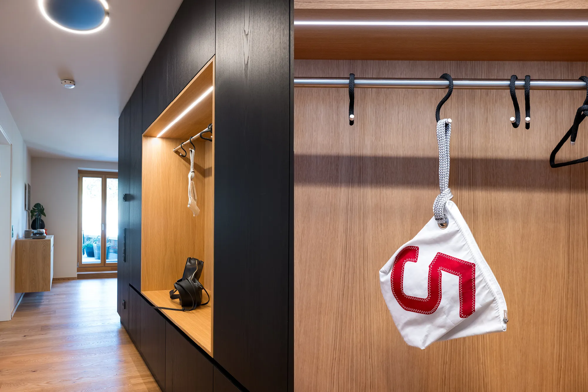 Garderobenschrank in Schwarz und Holz mit integrierter Kleiderstange und stimmungsvoller LED-Beleuchtung.