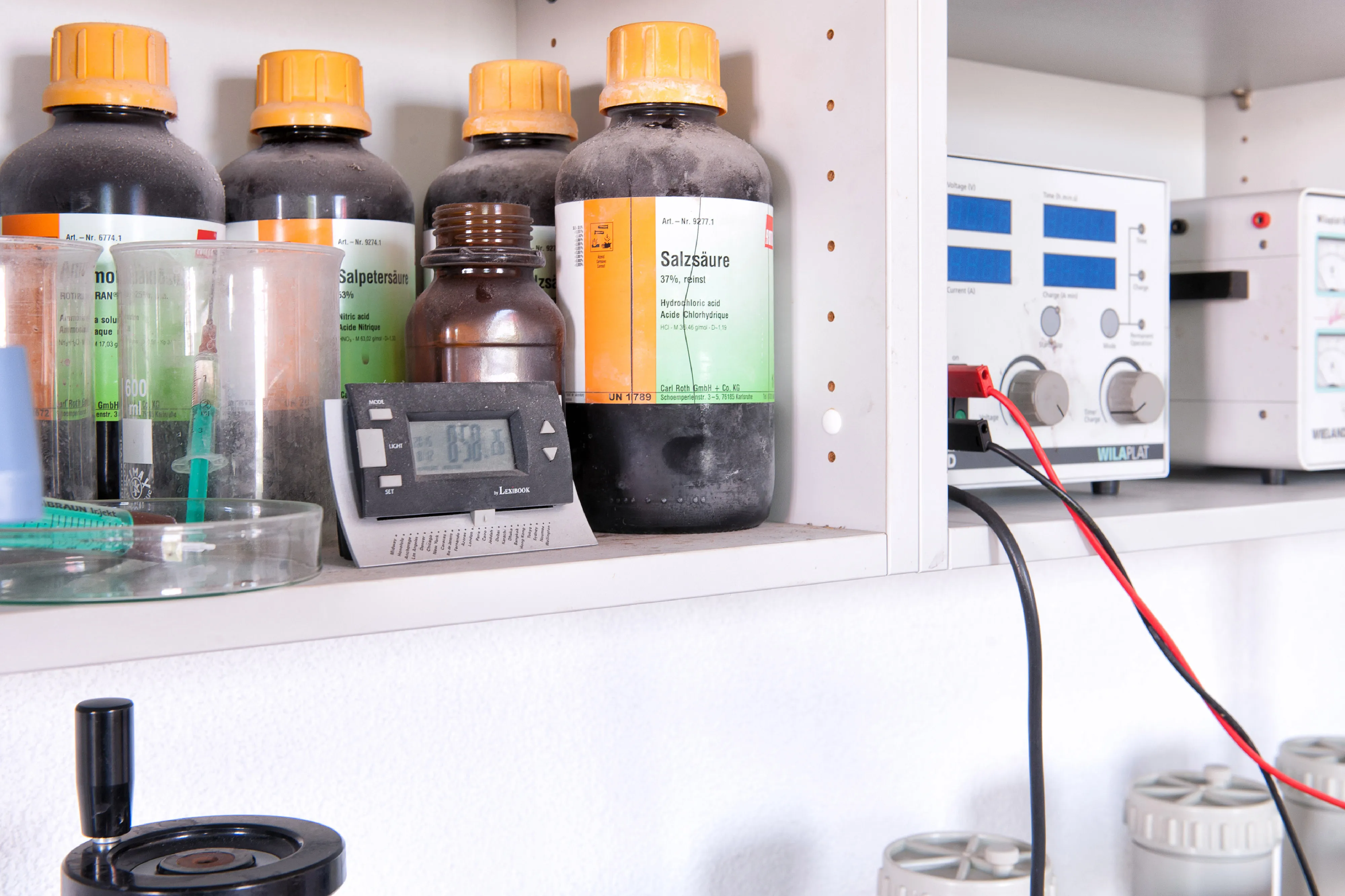 Detailansicht eines weiß beschichteten Wandregal-Fachs zur übersichtlichen und sicheren Aufbewahrung von Chemikalienbehältern.