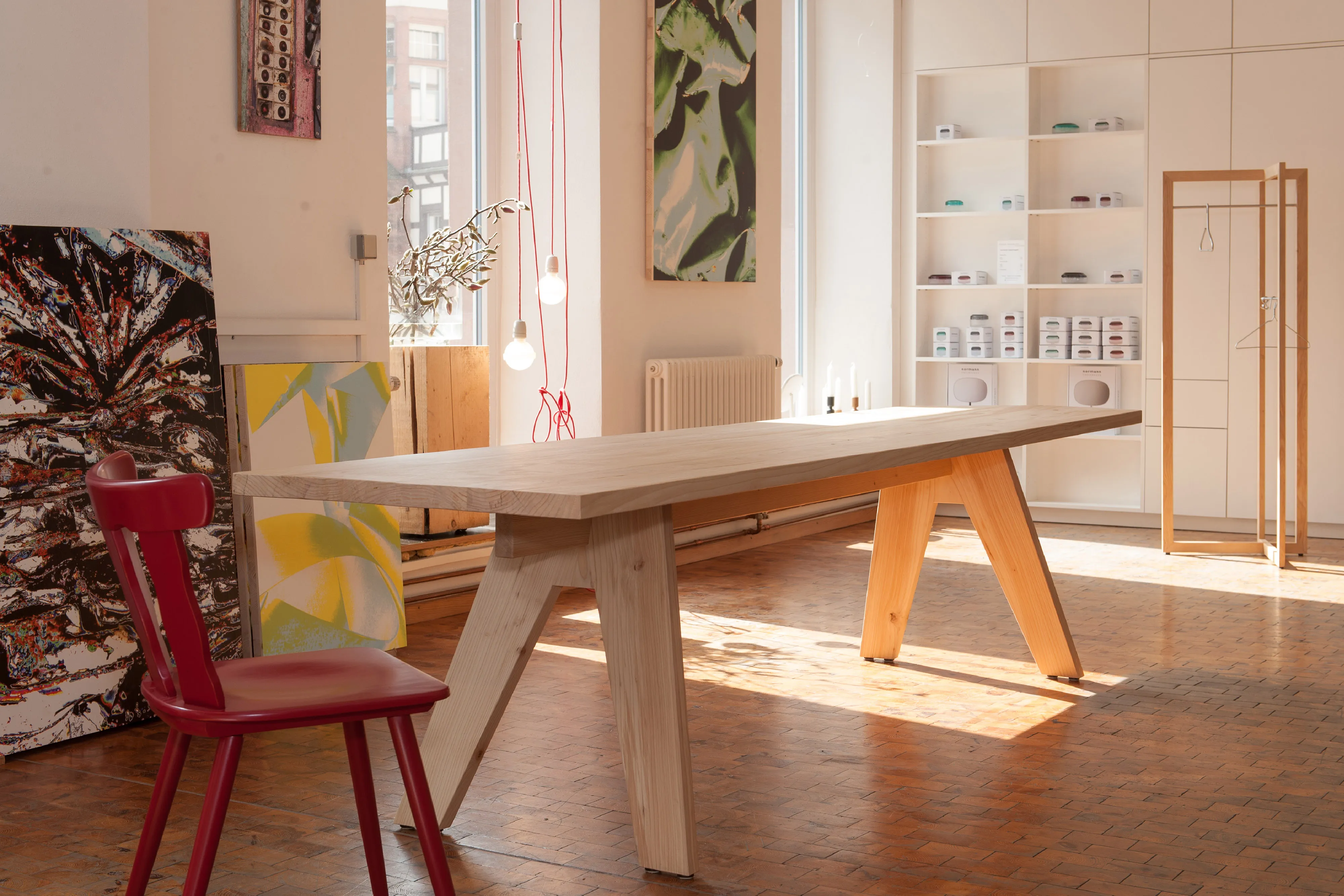 Großer Ess- oder Arbeitstisch aus hellem Echtholz mit auffälligen A-förmigen Tischbeinen in einem modernen Studio-Raum.