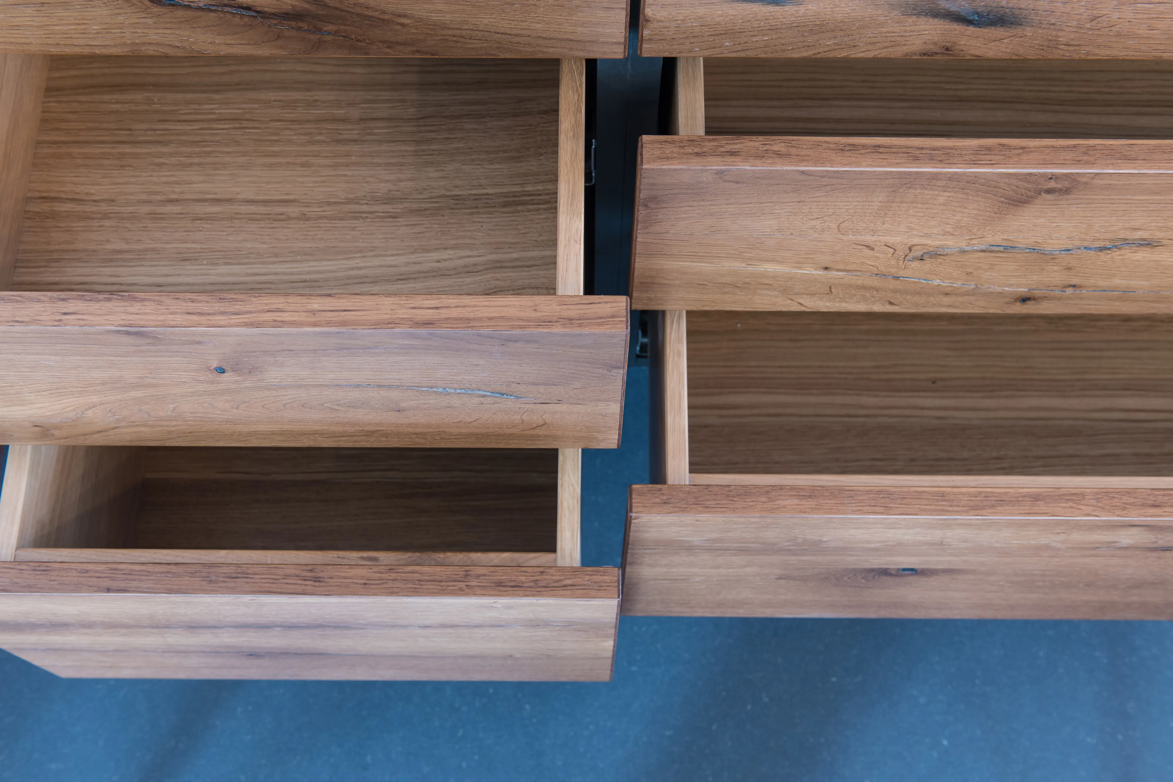 Draufsicht auf geöffnete, maßgefertigte Holzschubladen aus Wildeiche mit schlichter, eleganter Kantenverarbeitung