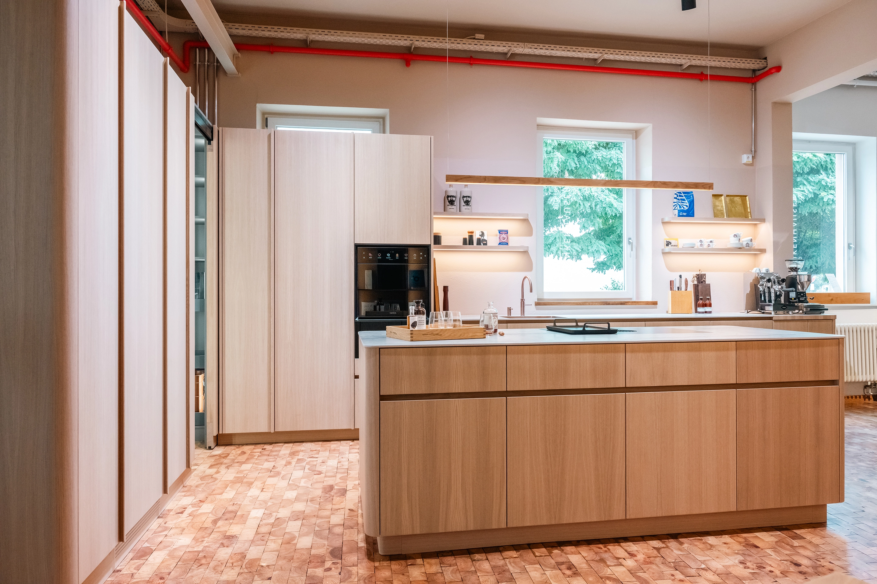 Großzügige Showroom-Küche mit Dingerstone Kochinsel, BORA Geräten, Quooker Armatur und Hera Lichtkonzept.