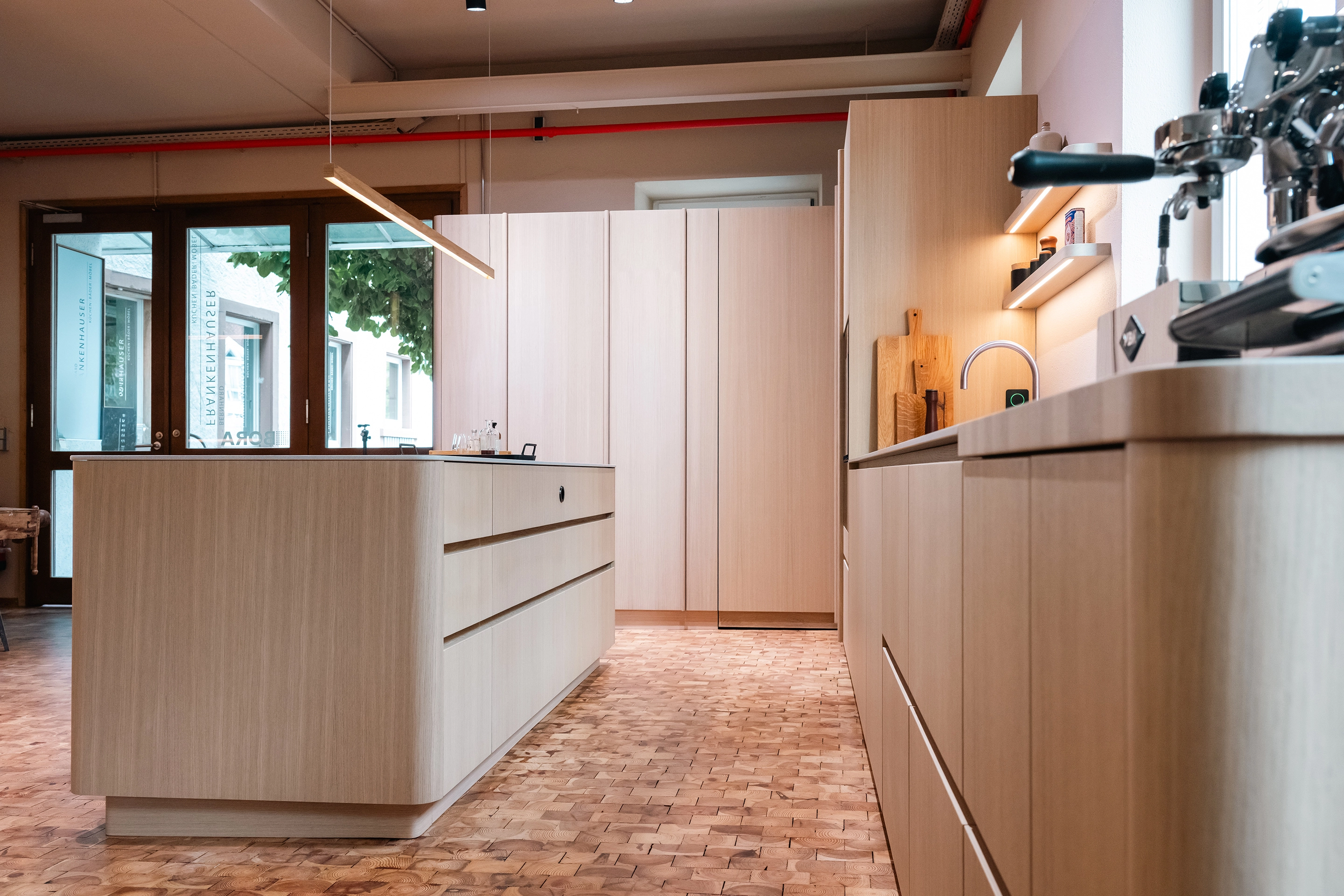 Seitenansicht der Holzküche mit Fokus auf die abgerundete Kochinsel und das integrierte BORA System.