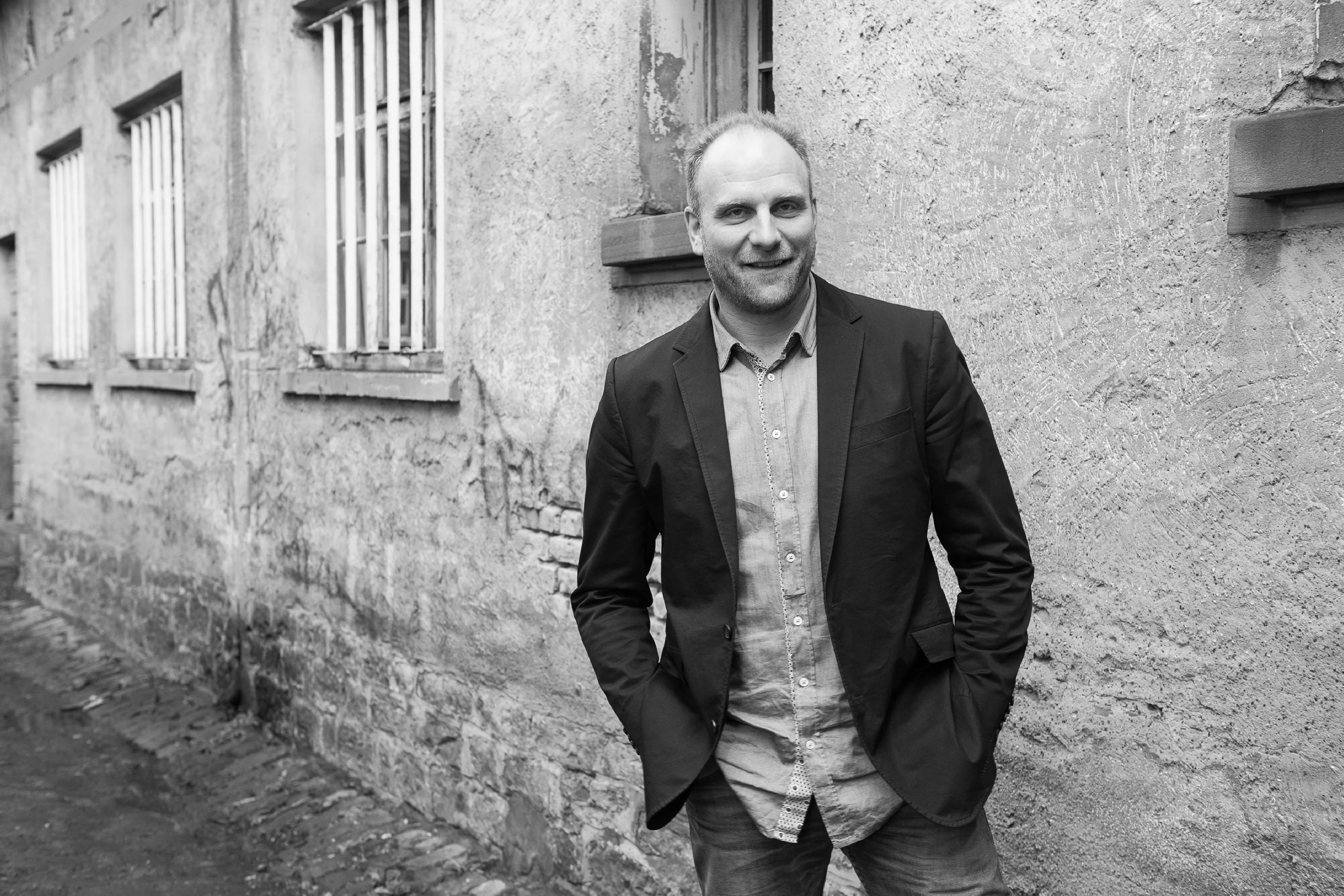 Bernhard Frankenhauser, Firmeninhaber und Schreinermeister im Sakko, der lässig vor dem Firmengebäude steht.