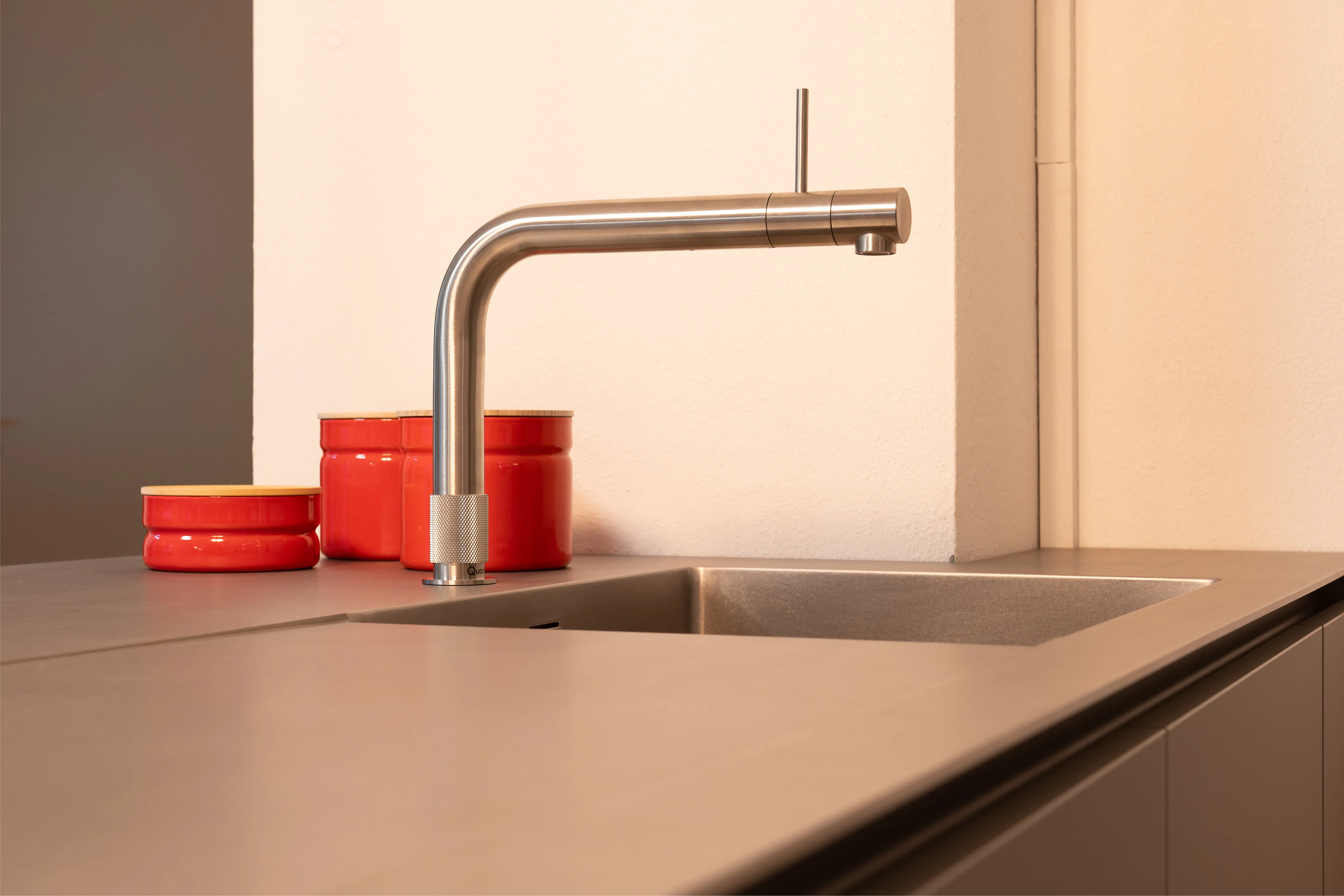 Nahaufnahme einer eleganten Edelstahl-Küchenarmatur über einem untergebauten Spülbecken auf grauer Arbeitsplatte